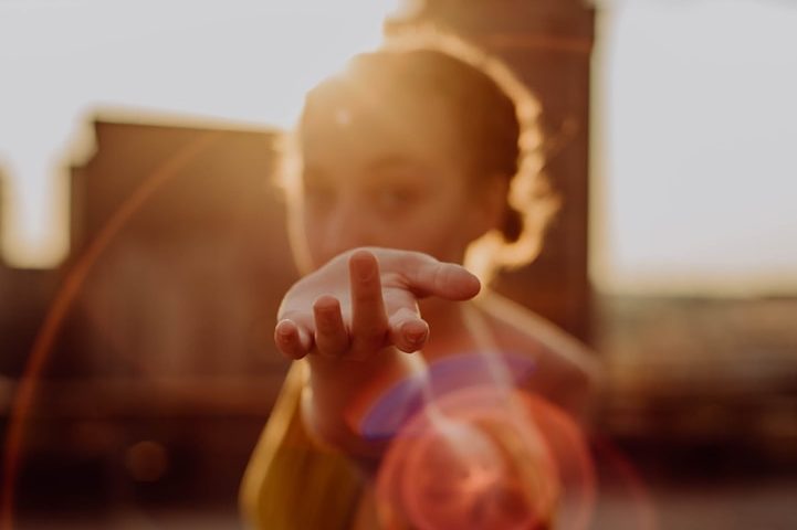 Zielgruppengerechte Anleitung steht im Vordergrund Frau streckt die Hand aus, Sonnenlicht hinter ihr erzeugt einen warmen, leuchtenden Effekt.